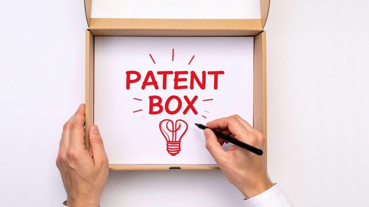 Mani che disegnano la scritta 'PATENT BOX' su un foglio bianco dentro ad una scatola di cartone aperta, a rappresentare i vantaggi del patent box rispetto al credito d'imposta.