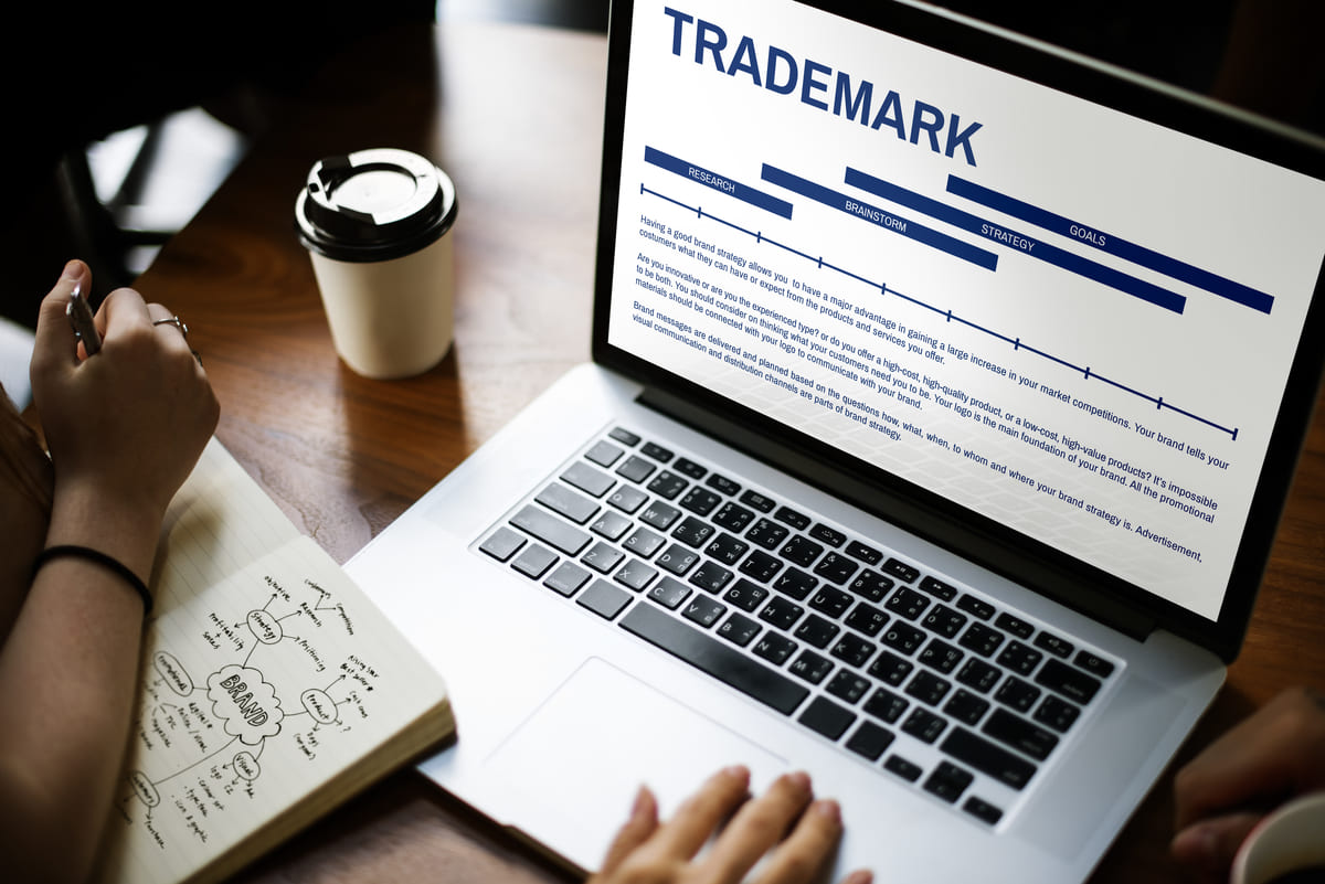 Un PC portatile appoggiato sul tavolo mostra una slide di spiegazione dei Trademark, simbolo dell'importanza di brevetti, disegni e marchi per le PMI.